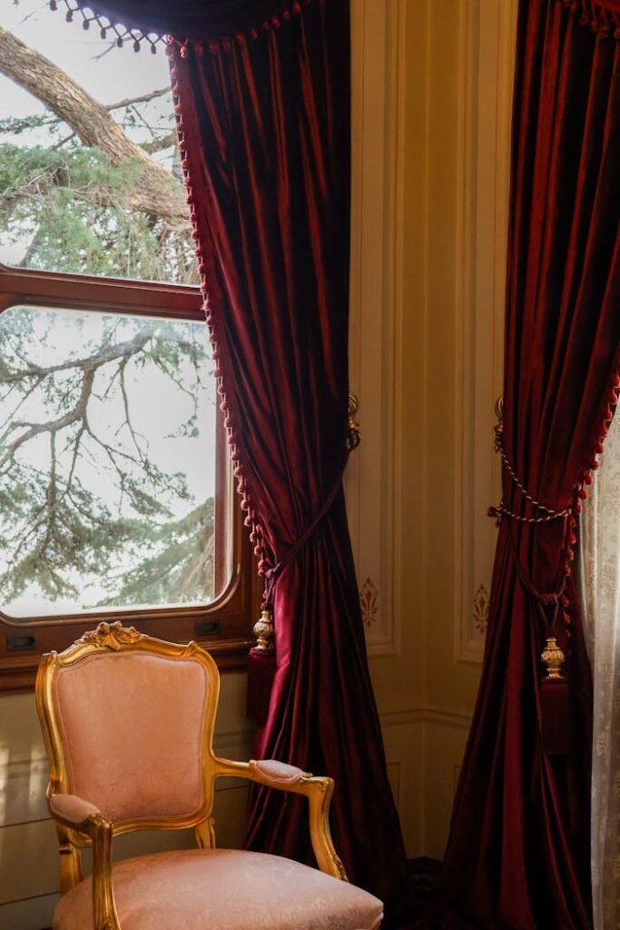 A luxurious vintage room with red velvet curtains and a gold-framed chair.